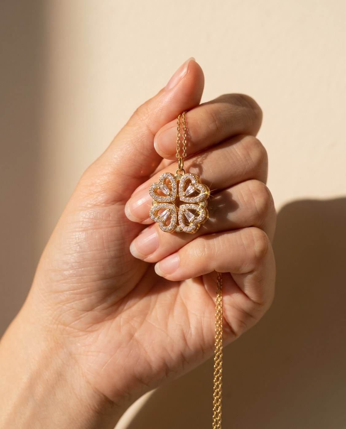 Hand holding the folded gold four leaf clover pendant